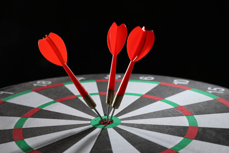 Targeting. Dart board with arrows on black background, closeupの写真素材