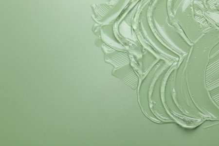 Collagen gel on green background, above view. Space for text