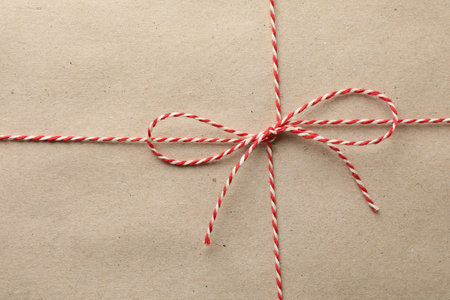 Gift wrapped in kraft paper and bow as background, top viewの写真素材