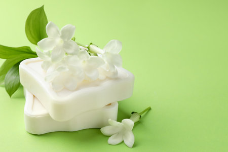 Bars of soap and jasmine flowers on light green background, closeup. Space for textの写真素材