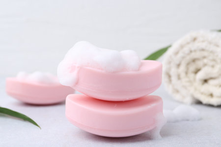 Soap bars with foam on white table, closeup
