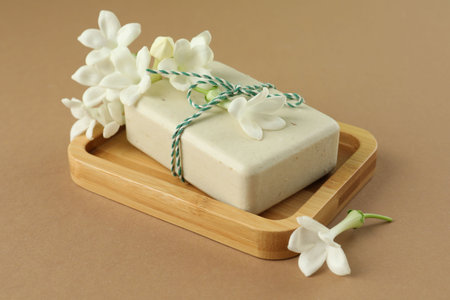 Bar of soap and jasmine flowers on light brown background, closeupの写真素材
