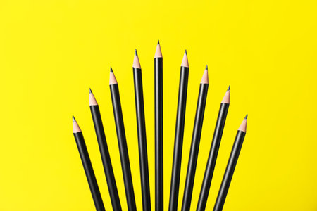 Many sharp graphite pencils on yellow backgroundの写真素材