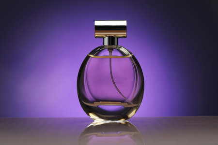 Bottle of perfume on mirror surface against purple gradient backgroundの写真素材