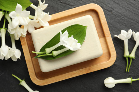 Bar of soap and jasmine flowers on black table, flat layの写真素材