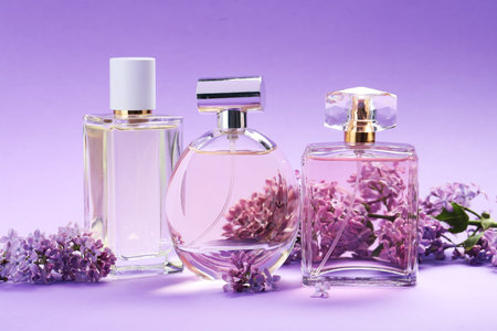 Bottles of perfumes and branches with lilac flowers on purple gradient background, closeupの写真素材