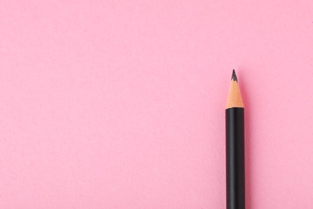 Sharp graphite pencil on light pink background, top view. Space for textの写真素材