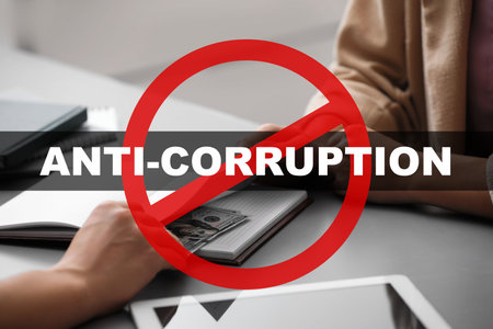 Anti-corruption. Man offering bribe money at table indoors, closeup. Red stop signの写真素材