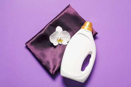 Bottle of fabric softener, orchid flower and color cloth on purple background, top viewの写真素材
