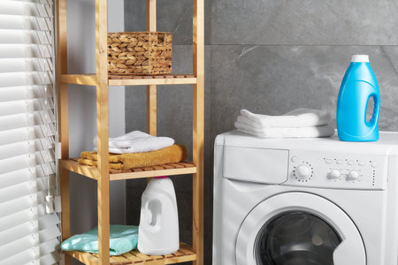 Bottle of fabric softener and towels on washing machine indoorsの写真素材