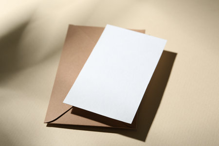 Blank greeting card and paper envelope on beige background, closeupの写真素材