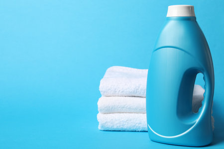 Bottle of fabric softener and towels on light blue background, space for textの写真素材