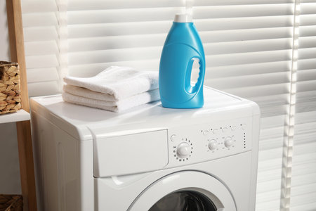 Bottle of fabric softener and towels on washing machine indoorsの写真素材