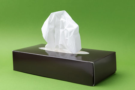Box with paper handkerchiefs on green background