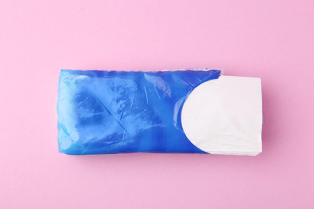Paper handkerchiefs in package on pink background, top view