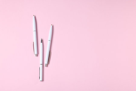 Ballpoint pens on pink background, flat lay. Space for textの写真素材