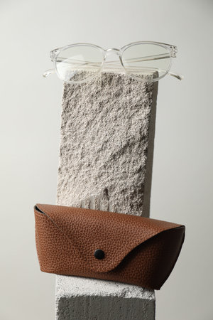 Stylish glasses and case on stone surface against light grey background