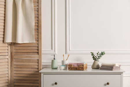 Clean waffle towels and other bath products on white dresser in bathroom