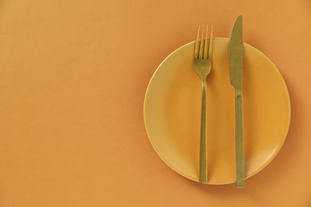 Stylish plate and cutlery on orange background, top view. Space for textの写真素材