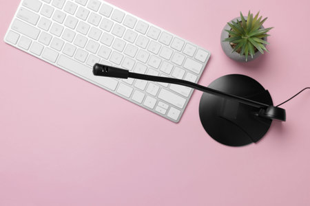 Professional microphone, computer keyboard and floral decor on pink background, flat lay. Space for...