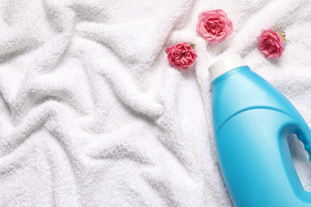 Bottle of fabric softener and flowers on terry towel, flat lay. Space for textの写真素材