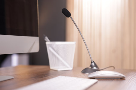 Microphone and computer on wooden desk indoorsの写真素材