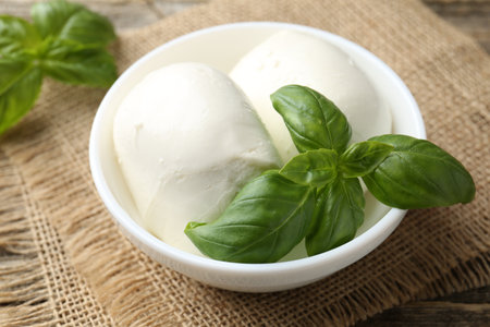 Tasty mozzarella cheese and basil on wooden table, closeupの写真素材