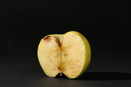 Half of damaged apple on black backgroundの写真素材
