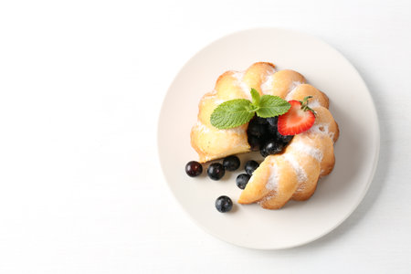 Tasty bundt cake with powdered sugar, berries and mint on white background, top view. Space for textの写真素材
