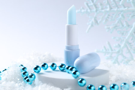 Moisturizing lip balm and Christmas decor on artificial snow, closeup. Winter careの写真素材