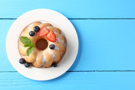 Tasty Bundt cake with powdered sugar and berries on light blue wooden table, top view. Space for textの写真素材