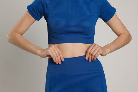 Woman with flat belly on gray background closeupの写真素材