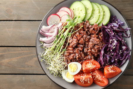 Tasty salad with brown rice on wooden table, top viewの写真素材