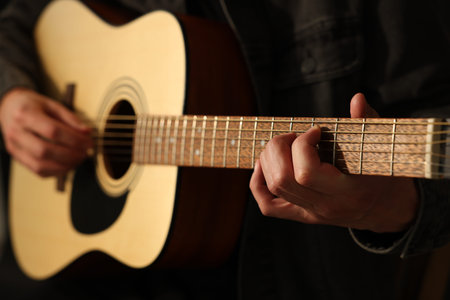 Man playing guitar on black background, closeup