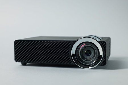 Modern video projector on light grey background, closeup