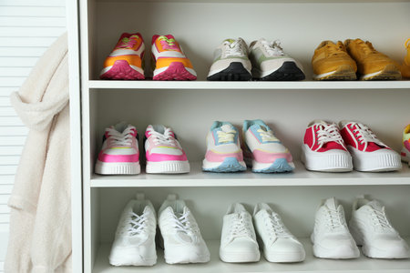 Different footwear on shelves indoors, closeup. Shoe storage