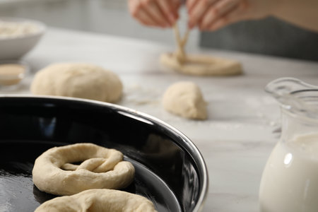 Woman shaping pretzels at table in kitchen, selective focusの写真素材