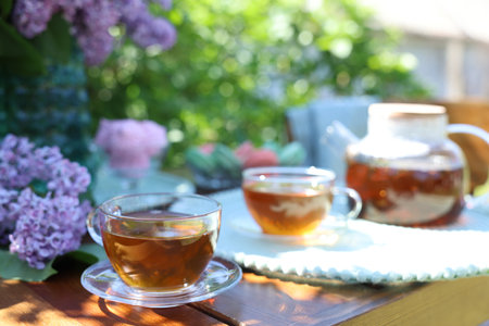 Beautiful lilac flowers and tea on wooden table in garden, closeupの写真素材