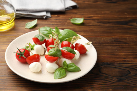Appetizers with mozzarella, tomatoes and basil on wooden tableの写真素材