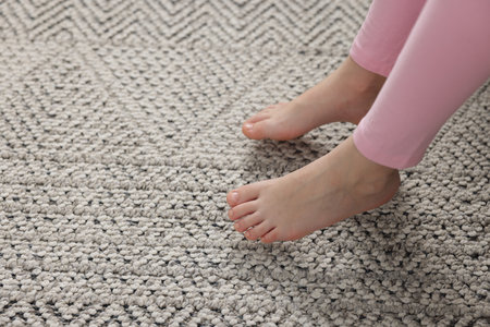 Girl above grey carpet at home, closeupの写真素材