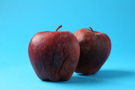 Damaged red apples on light blue backgroundの写真素材