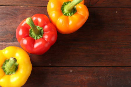 Ripe colorful bell peppers on wooden table, flat lay. Space for textの写真素材