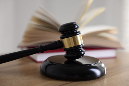 Judge's gavel and books on wooden table indoors, selective focus