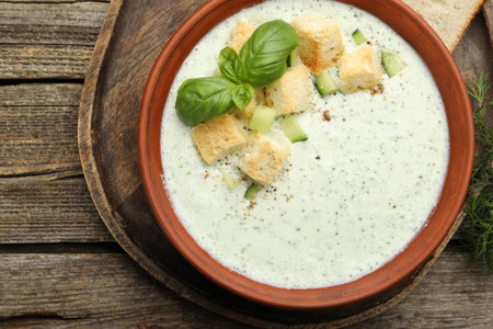 Tasty cucumber soup with croutons and basil on wooden table, top viewの写真素材
