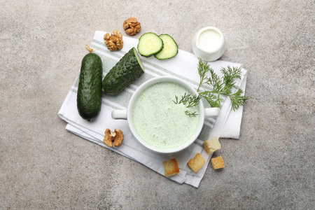 Tasty cucumber soup with dill, croutons, walnuts and vegetables on grey table, flat layの写真素材