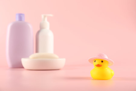 Cute rubber duck in hat, soap and bottles of cosmetic products on pink backgroundの写真素材