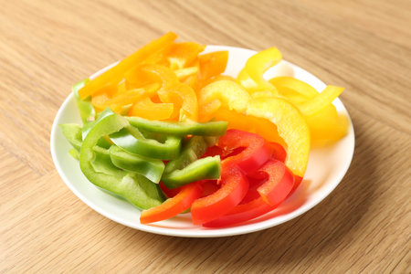 Slices of fresh colorful bell peppers on wooden table, closeupの写真素材
