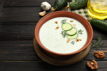 Tasty cucumber soup with dill, walnuts and ingredients on wooden table, closeupの写真素材