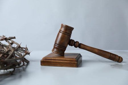 Judge's gavel and crown of thorns on white marble table