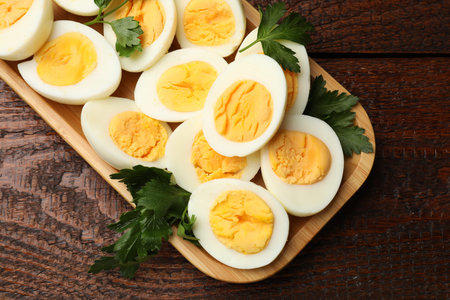 Boiled eggs and parsley on wooden table, top view